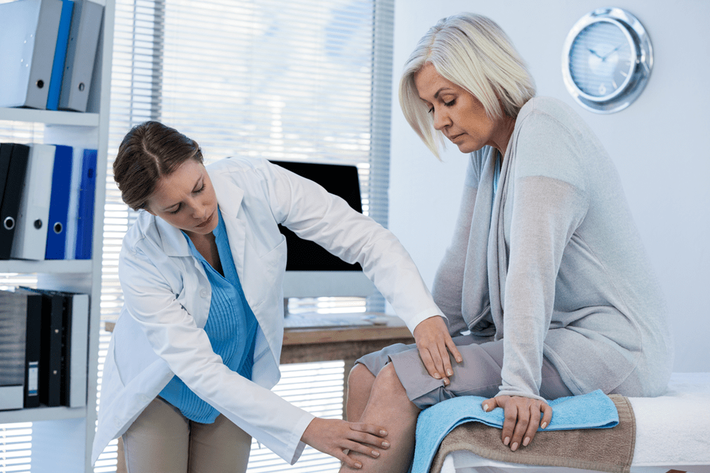 Doktor memeriksa pesakit dengan osteoartritis lutut